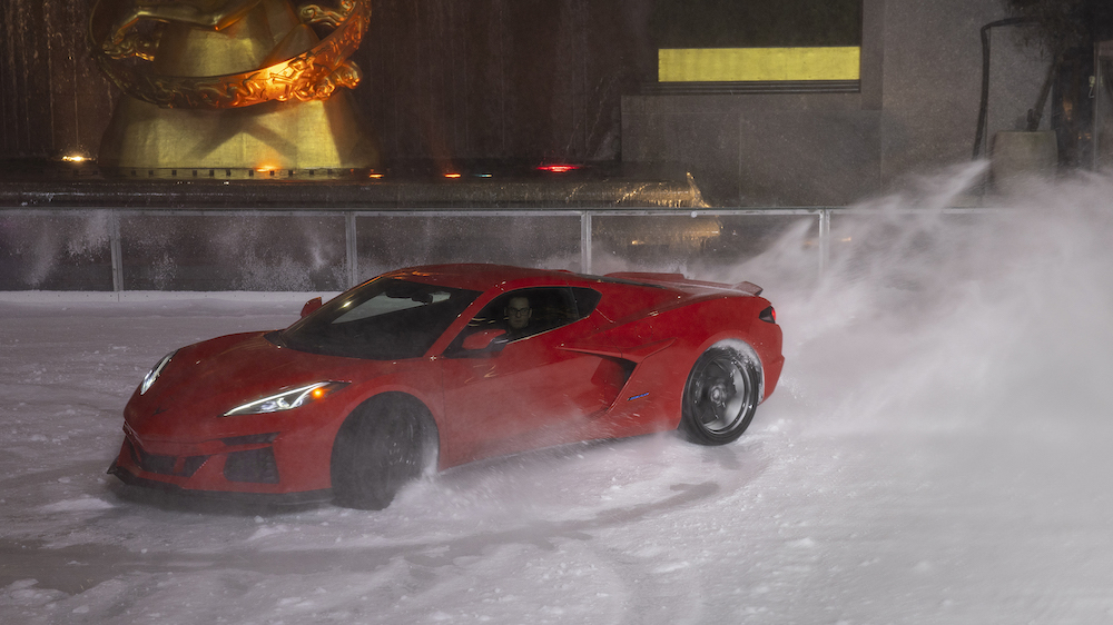 Front 3/4 view of 2024 Corvette E-Ray in Torch Red performing maneuvers on The Rink at Rockefeller Center. Pre-production model shown. Actual production model may vary. Model year 2024 Corvette E-Ray available 2023.