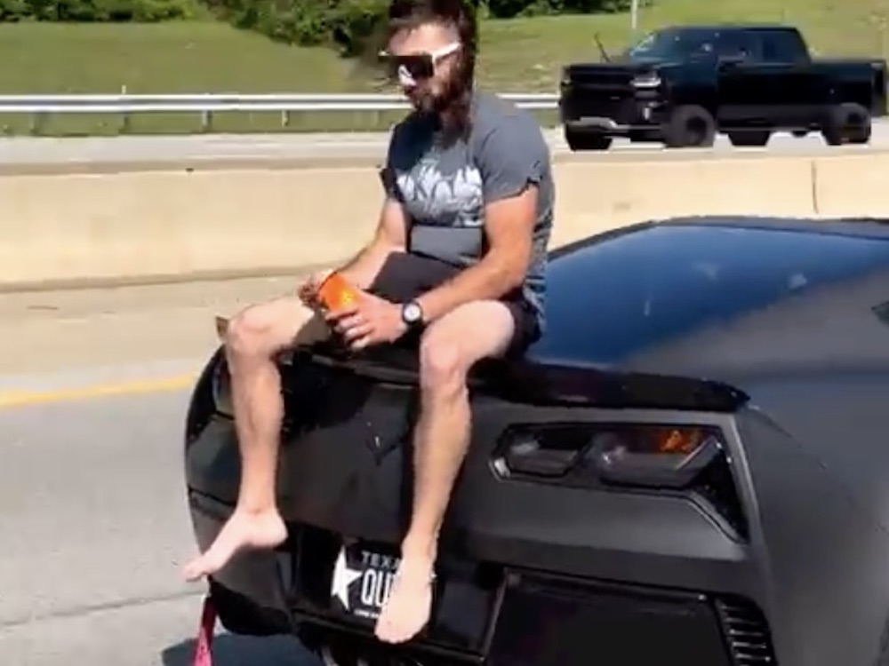 Man Sits on Back of C7 Corvette Driving Down Highway